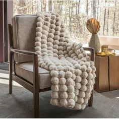 a chair with a blanket on top of it next to a table and vases