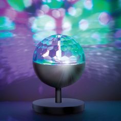 a glass ball sitting on top of a table next to a purple and green background