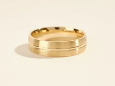 two gold wedding bands sitting next to each other on a white surface with no background