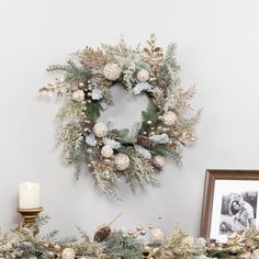 a christmas wreath is hanging on the wall next to a candle and framed photo in front of it