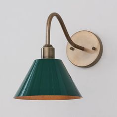 a green wall light mounted on the side of a white wall with a wooden arm