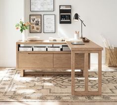 a wooden desk sitting on top of a rug next to a wall with pictures above it