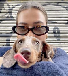 a woman wearing glasses holding a dog in her arms and looking up at the camera