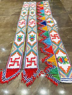 three rows of colorful beaded and tasseled items on the floor in a room