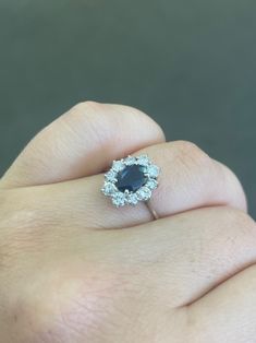 a woman's hand holding an engagement ring with a blue stone in the center