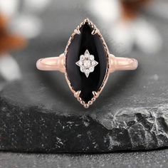 a black and white diamond ring on top of a rock