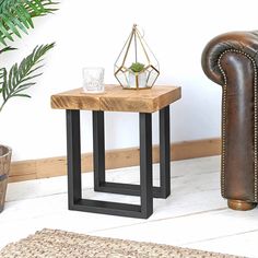 a small wooden table sitting on top of a white floor next to a brown couch