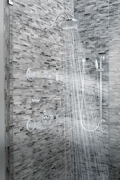 a shower head and hand held shower faucet in a modern bathroom with mosaic tiles on the walls