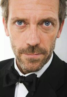 a man in a tuxedo and bow tie with blue eyes looking at the camera