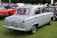 an old grey car is parked in the grass at a car show with other cars