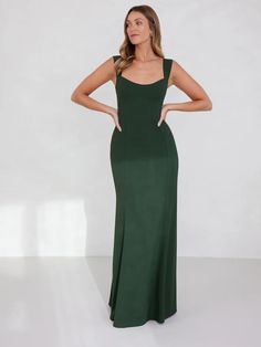 a woman in a long green dress standing with her hands on her hips and looking off to the side