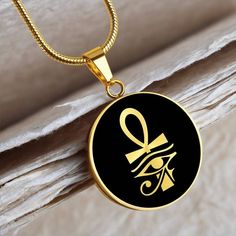 "This Ankh Necklace Is the Perfect Gift for all those Travel lovers, Whether for Yourself or a Loved One.  ➜ Our jewelry is made of high-quality surgical steel with a shatterproof liquid glass coating and an 18k gold finish option. ➜ Engrave onto the back of the Egyptian pendant your loved one's name, your wedding date, an anniversary, or anything else you want to remember and keep you close to her heart. You can add 2 lines and each up to 20 characters long. Each personalized Eye of Ra pendant offers exceptional craftsmanship that is fit to be an instant classic in your family. ➜ If you're not 100% satisfied with your purchase for any reason, please contact us and we will make it right. Your satisfaction is our ultimate goal. Explore all our Symbolic gifts here: https://www.etsy.com/shop/ Symbolic Black Stainless Steel Necklace, Symbolic Stainless Steel Medallion Jewelry, Stainless Steel Amulet Pendant Jewelry, Stainless Steel Round Amulet Jewelry, Spiritual Stainless Steel Jewelry Round Shape, Spiritual Stainless Steel Jewelry, Black Ankh Jewelry For Gifts, Black Stainless Steel Medallion Necklaces, Black Medallion Stainless Steel Necklaces