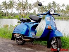 a blue scooter parked next to a body of water