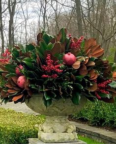 a large vase filled with lots of flowers on top of a stone bench in a park