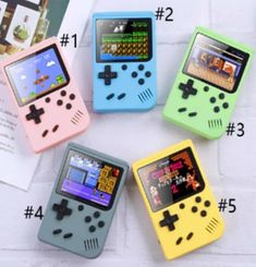 four different colored game controllers sitting on top of a white brick wall next to each other