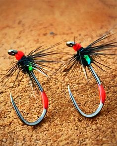 two black and red fishing hooks sitting on top of a wooden floor