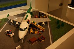 a model airplane is on display in a room with toy cars and trucks around it