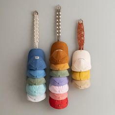 four baseball caps are hanging from hooks on the wall, one has a chain attached to it