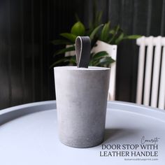 a concrete cup sitting on top of a white table next to a potted plant