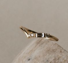 a yellow gold ring with three diamonds on it sitting on top of a marble slab