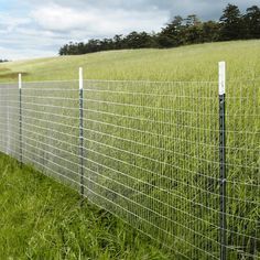 a wire fence in the middle of a grassy field