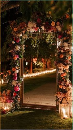 an archway decorated with flowers and candles is lit up for a wedding or reception at night