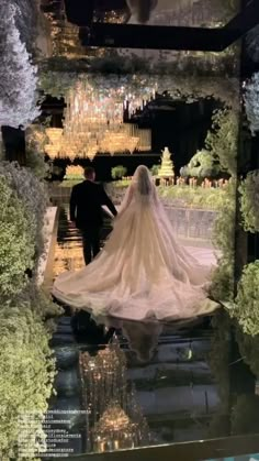 the bride and groom are walking down the aisle in their wedding dress, with chandeliers hanging from the ceiling