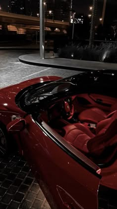 a red sports car parked in front of a building at night with its doors open