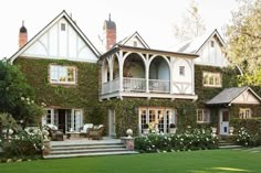 a large house covered in vines and flowers with stairs leading up to the front door