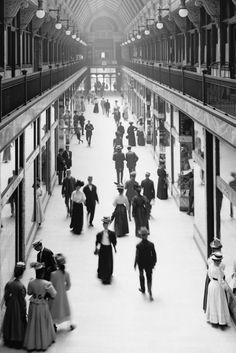 an old photo of people walking through a train station