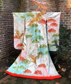 A spectacular example of a vintage Japanese formal wedding kimono, the outer-most garment thus referred to as a "robe," which a Japanese bride would wear over several other kimono layers, loosely draped and partly open at the bottom front (not tied with an obi belt). It is called an  known as "uchikake" in Japanese with its long "furisode" sleeves. Imagine this glorious garment hung on the wall decorating your home! The main design features Japanese red-crowned cranes (a symbol of filial piety and thus a symbol for marriage) swooping in and out of the pine tree boughs. All the cranes are painted and embroidered in gold while the pine branches alternate in red and green. The pine branch "shells" are filled with a traditional Japanese motif called "shippo" representing a tortoise shell. The Symbol For Marriage, Japanese Bride, Filial Piety, Wedding Kimono, Wall Decorating, Pine Branches, Obi Belt, Pine Branch, Japanese Silk