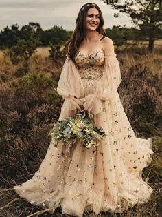 a woman in a wedding dress standing in the grass with her arms around her waist