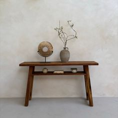 a wooden table with two vases on top of it and a plant in the middle