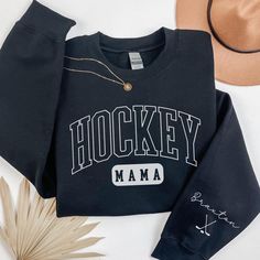 Embrace the spirit of the game and showcase your pride with our Custom Hockey Mom Sweatshirt featuring your name on the sleeve. This personalized Ice Hockey Mama Sweater not only keeps you warm but adds a stylish touch to your game-day wardrobe, making it the perfect custom gift for any dedicated hockey mom! 🏒 💕 ♥ PRODUCT DETAILS & SIZING This pre-shrunk, classic fit sweatshirt is made with air-jet spun yarn for a soft feel and reduced pilling. ♥ Pre-shrunk ♥ Classic fit with no center crease Hockey Mom Sweater, Black School Spirit Sweatshirt For Sports, Winter Fan Merchandise Tops With Team Logo, Winter Fan Merchandise Top With Team Logo, Black Sports Fan Sweatshirt For Sports Season, Black Pre-shrunk Sweatshirt For Fan Merchandise, Pre-shrunk Black Sweatshirt For Fan Merchandise, Black Collegiate Sweatshirt With Team Name, Long Sleeve T-shirt With Lettering For Sports Events