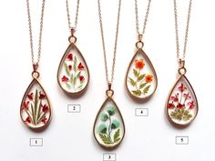 four pendants with flowers painted on them are shown in three different colors and sizes