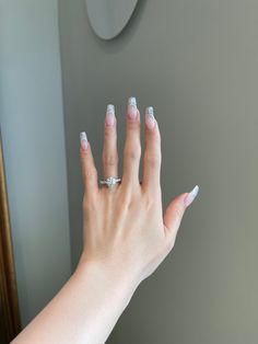 a woman's hand with white and silver nail polish on her nails, in front of a mirror