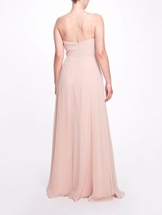 a woman in a long pink dress is looking down at the back of her dress