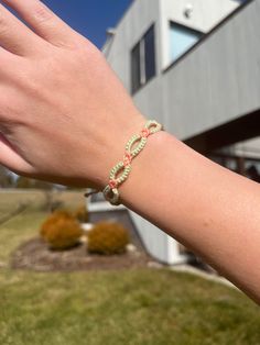 a person's hand with a bracelet on it in front of a building and grass