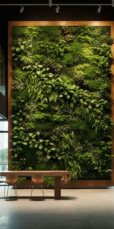 a living wall with green plants on it in an office building, surrounded by chairs and tables