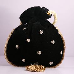 a black purse with white flowers and pearls on the front, sitting on a table