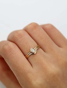 a woman's hand wearing a gold ring with a diamond on the middle finger