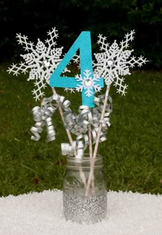 the number four is placed in a mason jar filled with silver and blue snowflakes