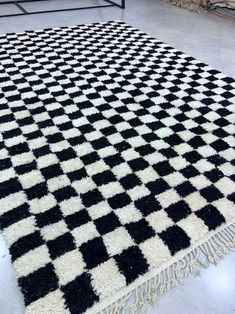 a black and white checkered rug with fringes on the floor in a room