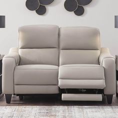 a white leather reclining sofa sitting in front of a wall with two circles on it