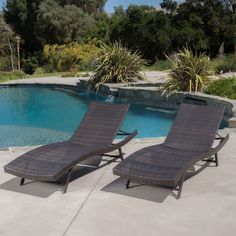 two lounge chairs sitting next to a swimming pool