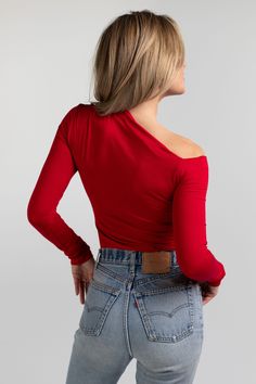 a woman with her back to the camera, wearing jeans and a red top that has one shoulder open