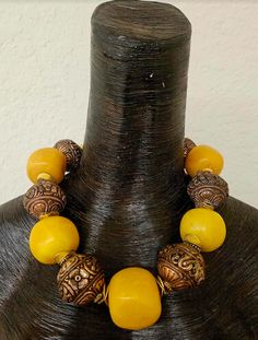 This stunning homage to Iris Apfel is from my private collection and is new and unworn. Five big, bold and chunky predominantly yellow (with a tinge of orange) Copal Amber beads are alternated with huge and ornate Tibetan Copper Repousse Beads. Each copal bead ranges in size from the smallest at 1.5" to the largest at 1.75". I did the water floatation test on these beads and they did indeed float! Separating all the large beads is a pair of burnished gold tone metal wavy potato chip spacers. Thi Amber Beaded Necklaces With Large Beads For Festival, Amber Beaded Necklace With Large Beads For Festival, Artisan Amber Necklaces With Large Beads, Artisan Necklace With Large Beads For Rituals, Traditional Amber Jewelry With Colorful Beads, Brown Large Beads Jewelry For Festivals, Large Beads Necklaces For Rituals And Festivals, Traditional Gemstone Bead Necklaces, Brown Large Beaded Jewelry For Festivals