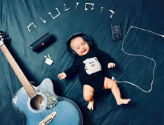 a baby is laying next to a guitar and headphones