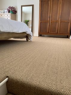 a bed sitting on top of a carpeted floor next to a dresser and mirror