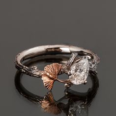 "A handmade twig and Ginkgo leaf ring set with a pear-shaped diamond. The ring displays a beautiful twig pattern along with a Ginkgo leaf that creates a pleasantly asymmetrical result. A delicate, handmade engagement ring made in two gold colors and set with a natural white diamond of high quality. The grooves in the band are plated with black rhodium which emphasizes the texture. if you prefer not to apply the black rhodium that is fine. I can also use white, rose, or yellow gold for the band and the leaf for the same price. Diamond - 100% natural, conflict-free certified diamond (you can also select a lab-grown diamond) Weight - The picture diamond weights 0.8ct, you can select a different diamond size at the diamond selection menu Color - G Clarity - SI If you are looking at this ring t Black Gem Ring, Copper Engagement Ring, Tree Engagement Ring, Twig And Leaf Engagement Ring, Ginkgo Ring, Luxury Leaf-shaped Nature-inspired Jewelry, Ginkgo Leaf Ring, Asymmetrical Engagement Ring, Yellow Gold Leaf Shape Nature-inspired Jewelry